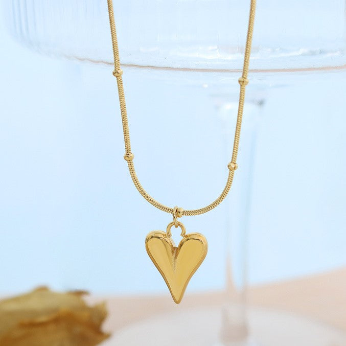 Shop now the Love Heart Pendant Necklace from Amore Jewellery! This stunning necklace features a heart-shaped pendant made of high-quality surgical titanium steel, 18K gold plated for a luxurious finish. The bright metal gleams, adding an easy-chic touch to your look. Available in gold and silver